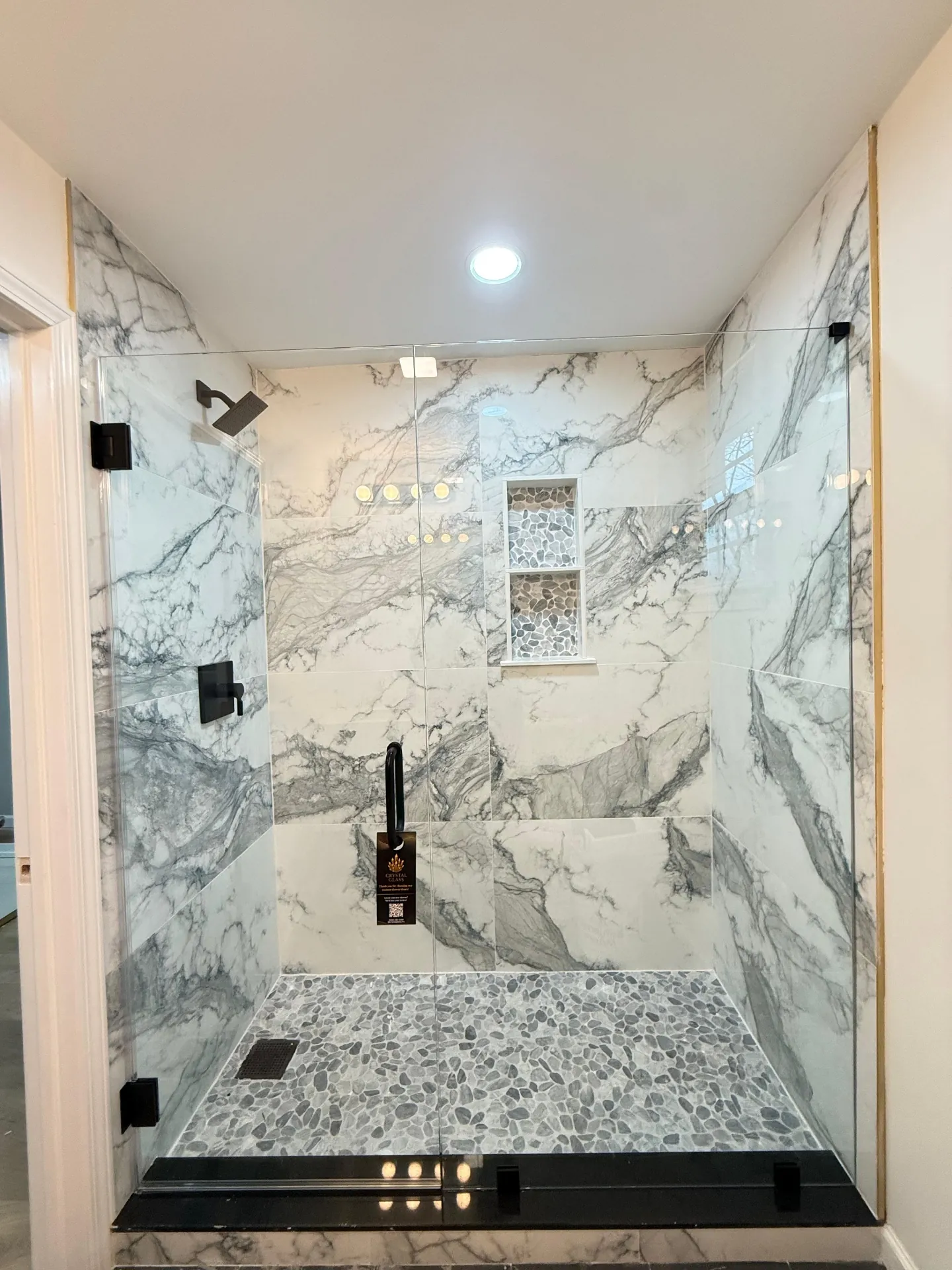 Marble shower with black hardware and frameless glass